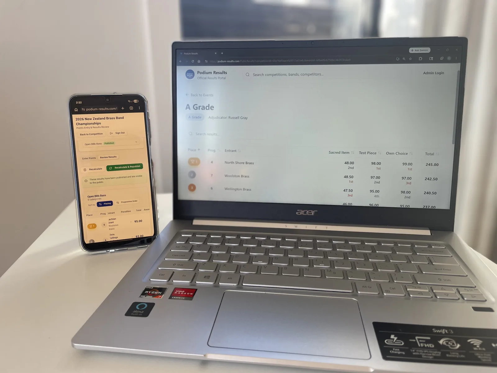 Published results open on a laptop and phone side by side at a venue